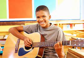 child with a smile holding a guitar